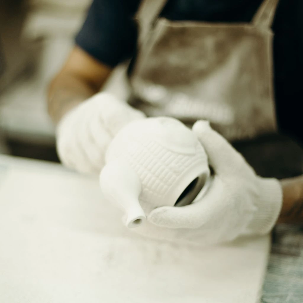 Master potter at a fifth-generation Bavarian porcelain atelier shaping a cup on the wheel.